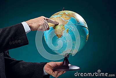 A man in suit holding globe and pointing at Africa continent. Business, education and travel concept Stock Photo