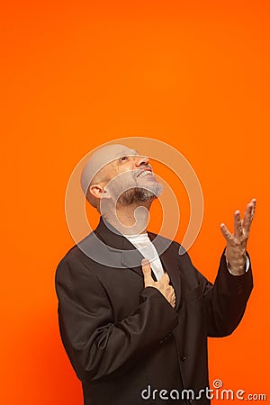 Man in suit jacket, bearded and bald looking up and making gestures Stock Photo