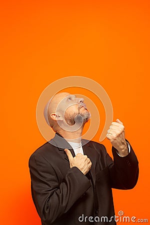 Man in suit jacket, bearded and bald looking up and making gestures Stock Photo