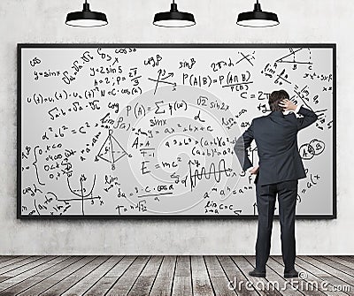 Man in suit looking at whiteboard with formulas Stock Photo