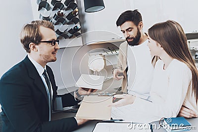 A man in a suit sits at a table with buyers. Stock Photo