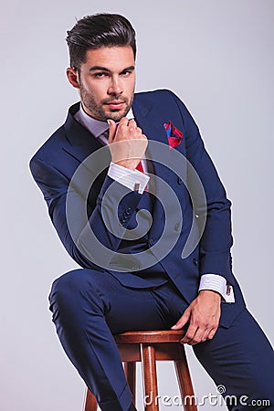 Man in suit sitting in studio while touching chin Stock Photo