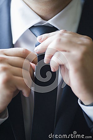 A man in a suit straightens his tie, close-up Stock Photo