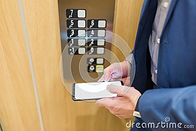 Man in suit using blank screen mobile phone inside of the elevator in business office building Stock Photo