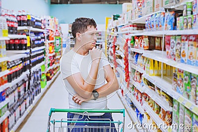 Man in the supermarket, customer thinking, choose what to buy Stock Photo