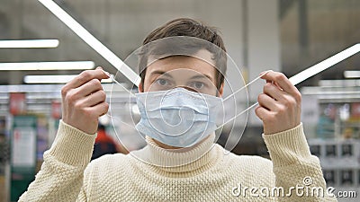 Man in a supermarket relieved to remove the medical mask. The coronavirus pandemic is over. Life is wonderful. Stock Photo