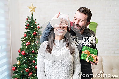 Man Surprising Lover With Christmas Gift At Home Stock Photo