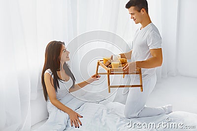 Man surprising woman with breakfast in bed Stock Photo