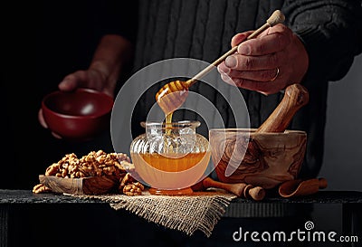 Man in a sweater prepares a breakfast of walnuts and honey Stock Photo