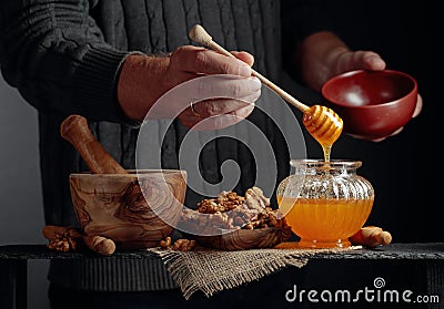 Man in a sweater prepares a breakfast of walnuts and honey Stock Photo