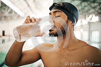 Man, swimmer and drinking water for hydration, exercise or training workout at indoor swimming pool. Active and thirsty Stock Photo