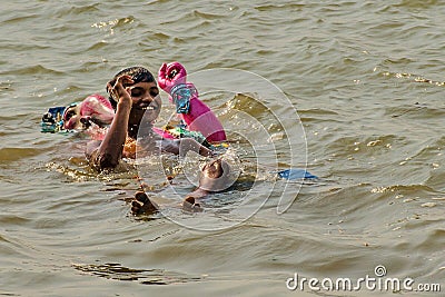 Man swimming with Ganesha idol Editorial Stock Photo