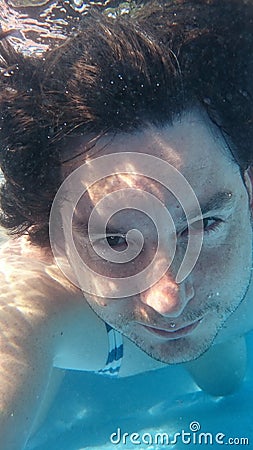 Man in swimming pool underwater. Male diving from closeup portrait front view. Stock Photo