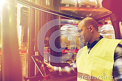 Man with tablet pc operating forklift at warehouse Stock Photo