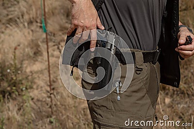 Man in tactical clothes shooting from a pistol, reloading the gun and aiming at the target in the open-door Shooting range. Stock Photo