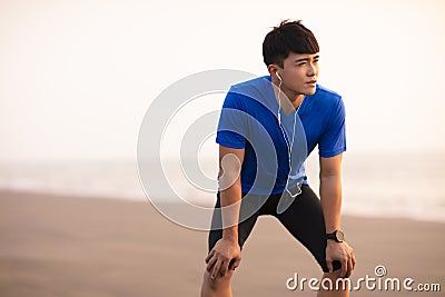 Man take break after running on beach at sunset Stock Photo