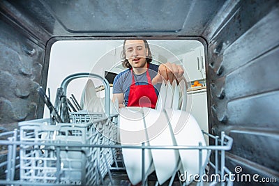 Man take out plates from the dishwasher machine Stock Photo