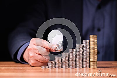 Small light bulb step up on the heap coins Stock Photo