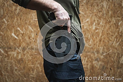 The man takes out a tactical pistol from his holster, close-up photo without a face Stock Photo