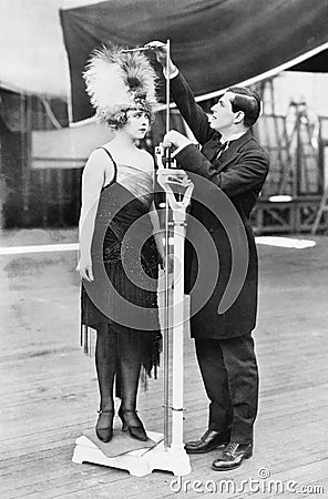 Man taking a measurement of a woman with an oversized hat Stock Photo