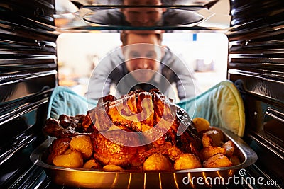 Man Taking Roast Turkey Out Of The Oven Stock Photo