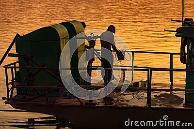 Man taking a shower at the end of working day over Chindwin river at sunset Editorial Stock Photo
