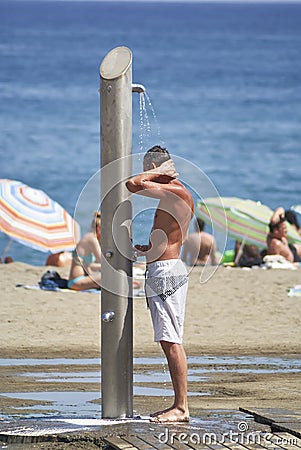 A man taking a shower on the beach in Malaga in Spain during the summer Editorial Stock Photo