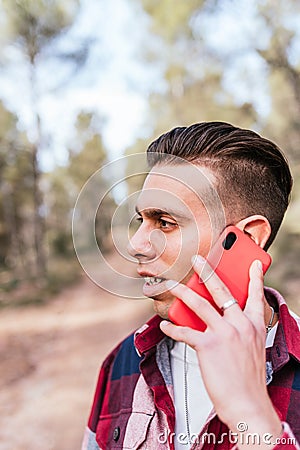 Man talking on smartphone on path between trees Stock Photo