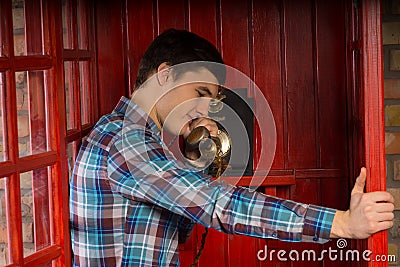 Man talking on a telephone in a booth Stock Photo