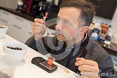 man tasting coffee in kitchen Stock Photo