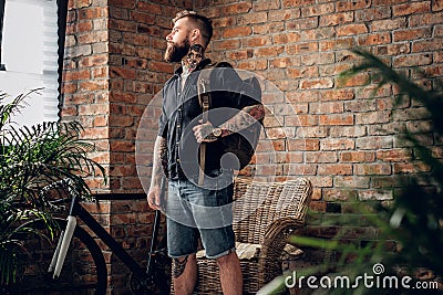 A man with tattoos on his arms holds urban backpack. Stock Photo