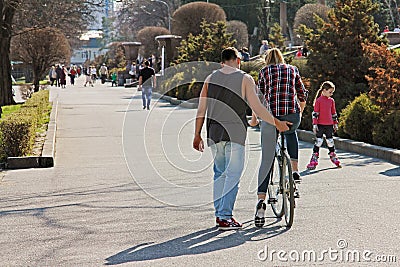 Man teaches a woman to ride a bicycle in park in Volgograd Editorial Stock Photo