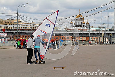 Man teaching woman how to ride skate with sail in the park Gorkogo Editorial Stock Photo