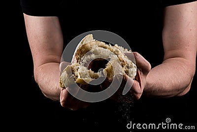 Man tearing a piece of bread in the middle of bread to share. Helping hands concept of sharing. Stock Photo