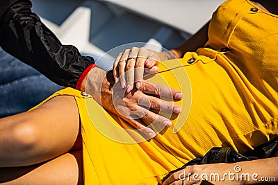 Man with tenderness holds his young pregnant wife by the belly,she is dressed in a bright yellow dress with buttons,her fingers Stock Photo