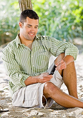 Man text messaging on cell phone at beach Stock Photo