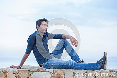 Man thinking sitting on a concrete bridge above the sea Stock Photo