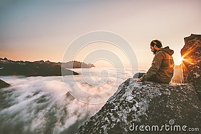 Man thinking sitting alone on cliff edge mountain top Stock Photo