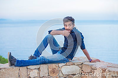 Man thinking sitting on a concrete bridge above the sea Stock Photo