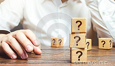 Man is in thought and blocks with questions. Pondering the problem, gathering all the facts. Make the right decision. Reasoning Stock Photo