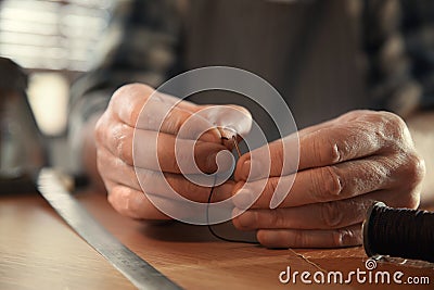 Man threading needle for leather working, closeup Stock Photo