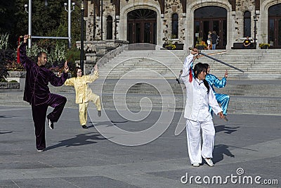 Man and three women in Asian outfits participating in a Tai Chi demonstration Editorial Stock Photo