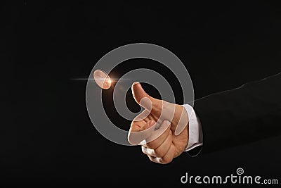 Man throwing coin on black background, closeup. Making decision Stock Photo