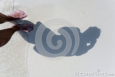 Man is throwing shadow to the fine sand of the beach Stock Photo