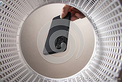 a man throws a non-working smartphone into a trash can. Bottom view from the trash can Stock Photo