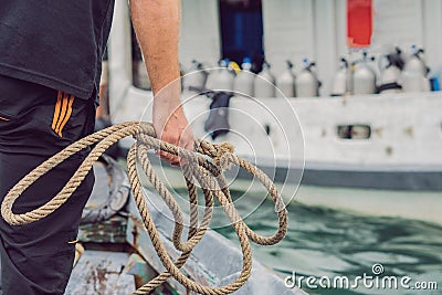 A man throws a rope to moor on a diver ship Stock Photo