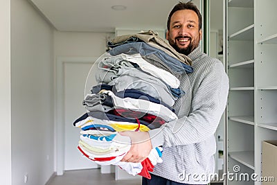 Man tiding clothes in large wardrobe closet with stylish clothes and home stuff Stock Photo