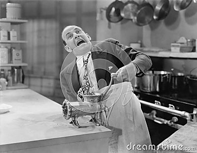 Man with tie stuck in meat grinder Stock Photo