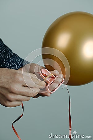 Man ties a golden balloon to a red ribbon Stock Photo