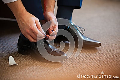 Man ties his shiney new black leather business shoes. Stock Photo